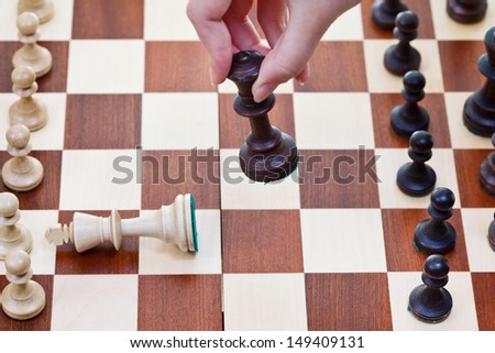 hand with Black King knocks white king on chess board