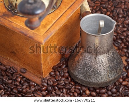 retro manual coffee mill and copper pot on many roasted coffee beans