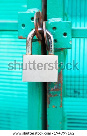 green door locked with steel padlock close up