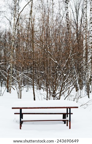 snow covered table on recreation ground of city park in winter