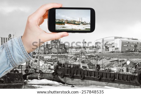 travel concept - tourist taking photo of Anadyr harbor in winter on mobile gadget, Chukotka, Russia