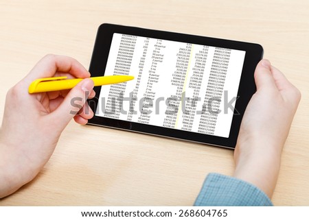 businessman touches by pen of tablet PC with sales data on screen at office table