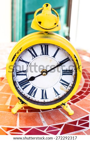 old yellow mechanical alarm clock on mosaic stone table