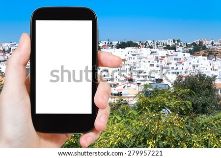 travel concept - tourist photograph Faro town in Portugal on smartphone with cut out screen with blank place for advertising logo