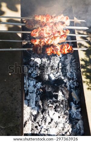 several kebab sticks preparing on outdoor grill