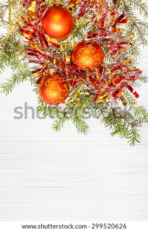 Christmas greeting card - border from three orange Xmas balls and tree branch on blank paper background