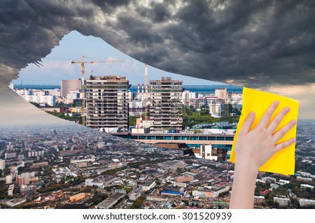 ecology concept - hand deletes dark city by yellow cloth from image and modern cityscape is appearing