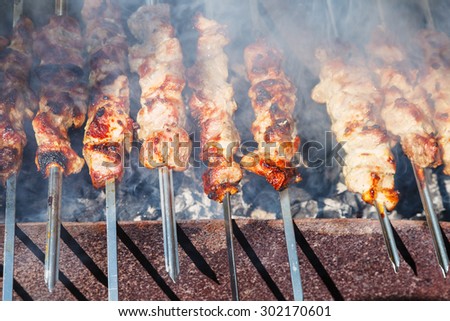 many shish kebab skewers preparing on outdoor grill