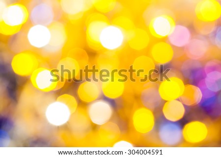 abstract blurred background - yellow and violet shimmering Christmas lights bokeh of electric garlands on Xmas tree