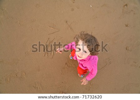 baby draws on sand beach
