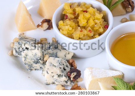 variety of cheeses on a white plate with sauce and spices close-up with shallow depth of field.