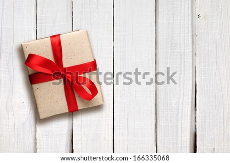 Gift box with red bow on white wooden background