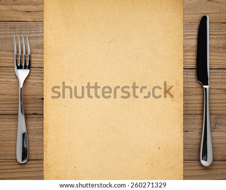 Old paper, fork and knife on wooden background