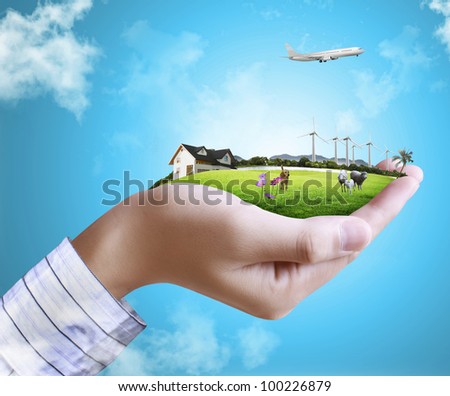 human hand holding a house ands nature