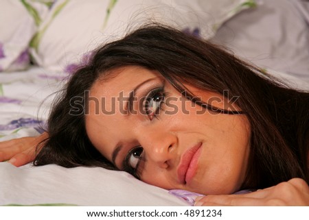 Attractive young woman in bed pondering