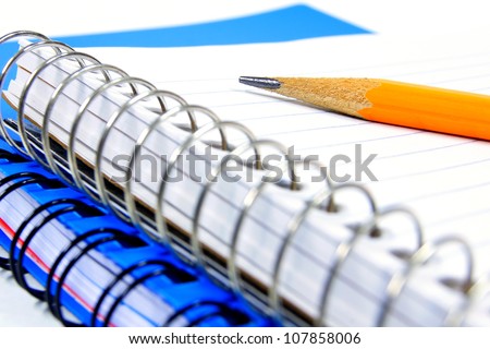 Close up of a pencil resting on a lined, coil notebook