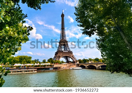 Eiffel Tower, iconic Paris landmark across the River Seine with green leaves vibrant blue sky, France