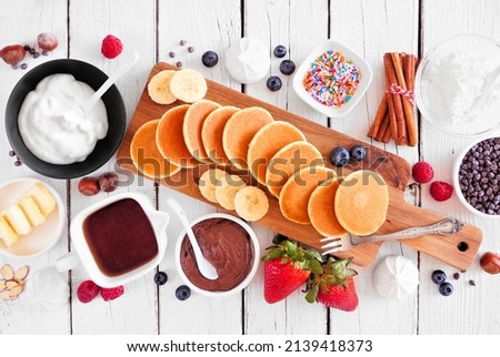 Similar – Image, Stock Photo Mini pancakes with butter and blueberries lie in a plate on a wooden table. Brunch, dessert for children, trending food. Space for text