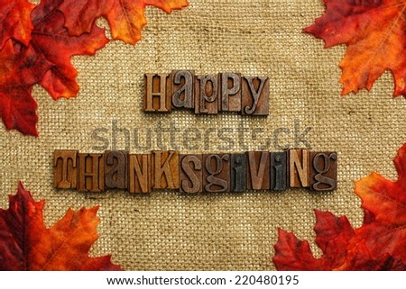 Happy Thanksgiving written with wooden letters on burlap with autumn leaves