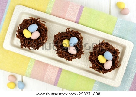 Plate of springtime chocolate nests filled with Easter eggs on a colorful background