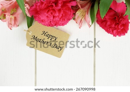 Happy Mother\'s Day gift tag with pink carnation and lily flowers border on white wood background