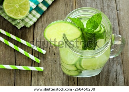Detox water with lime and cucumbers in a mason jar. Downward view on wood.