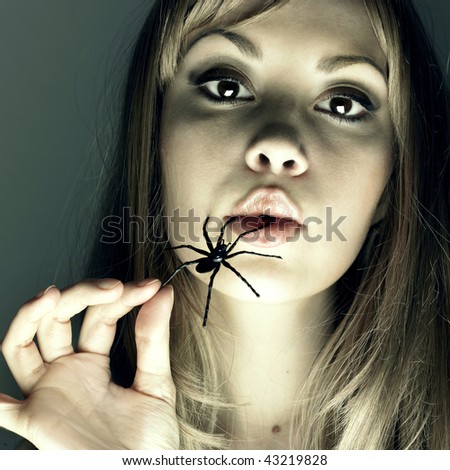 Studio portrait of the young woman eating the spider