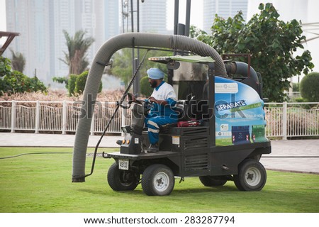 SHARJAH, UAE - APRIL 03, 2013: Worker in uniform on the car cleaning the lawn.