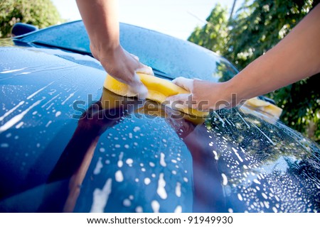 2 hands hold sponge over the car for washing