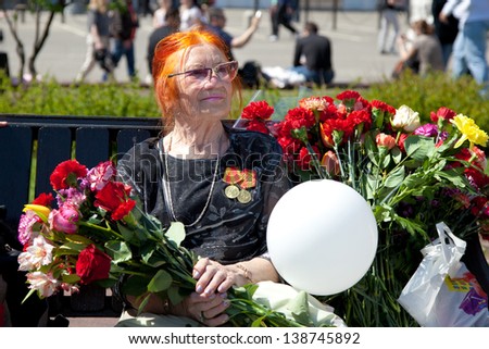 MOSCOW, RUSSIA - MAY 09: Female World War II veteran sitting on a bench with a bouquet of flowers on the Victory Day celebrations on May 9, 2013 in Moscow.