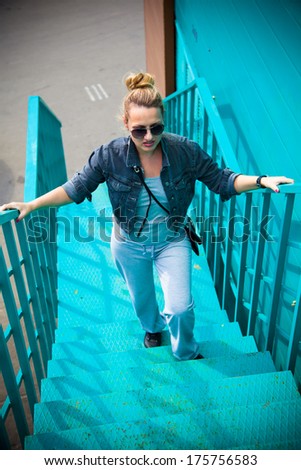 Young girl in sunglasses climbs the ladder of turquoise color