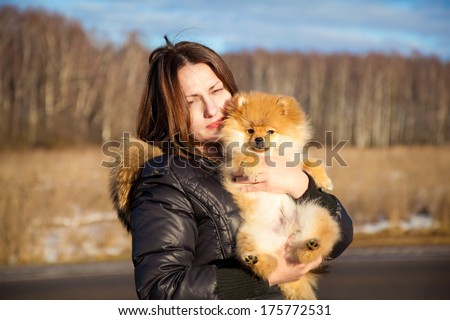 Beautiful girl holding a dog Spitz. Small breeds. Photographing outdoors.