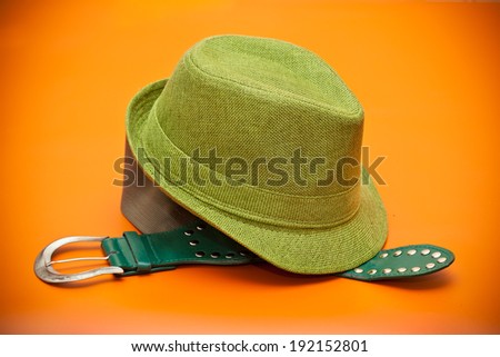 Green hat and a green belt with a buckle in western style on an orange background