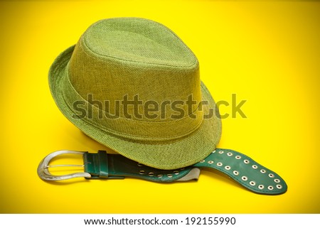 Green hat and a green belt with a buckle in western style on an yellow background