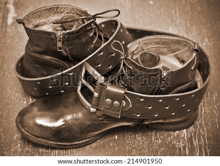 luxury leather shoes and a leather belt with buckle. cowboy style. vintage style. Photo toning in sepia