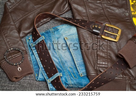 Brown leather jacket, jeans with a belt, shirt and bracelet on the arm
