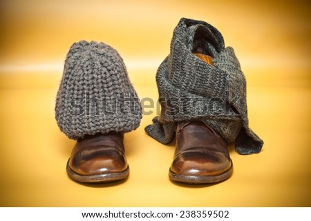 Leather shoes, gray knitted scarf and cap on an abstract background yellow. still life of clothes