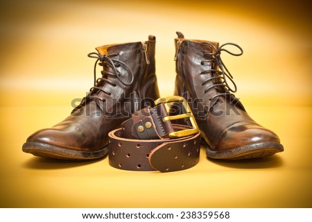 Fashion leather shoes, leather belt with gold buckle. Yellow abstract background