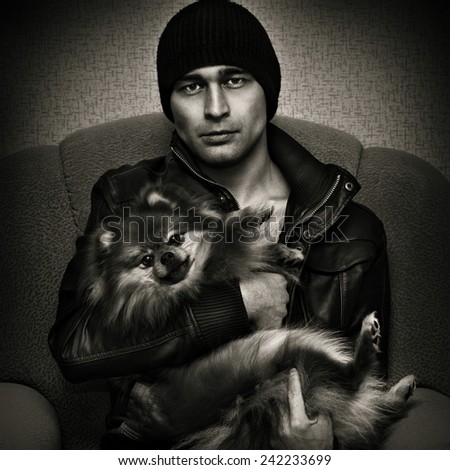 Harsh brutal man with Spitz dogs on their hands. Black and white photo in a dark style
