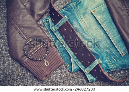 Details of clothes: jeans with a belt, leather jacket, bracelet on the arm. Photo toned in vintage style