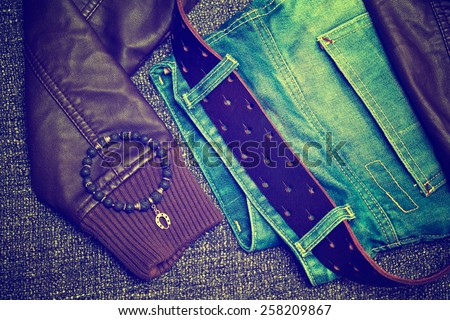 Clothing items and accessories: blue jeans with a leather belt, leather jacket, bracelet on the arm