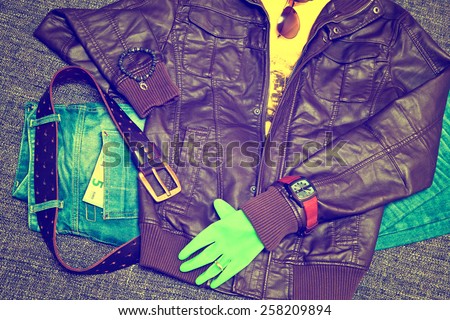 Fashionable clothes: blue jeans with a leather belt, leather jacket, T-shirt, watches, sunglasses, bracelet on the arm, glove, 5 Euro banknote