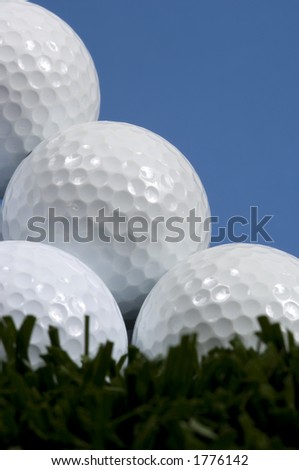 Golf ball pyramid on grass with blue sky