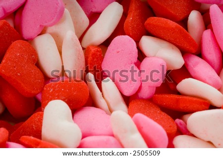 Extreme close-up of tiny candy hearts in red, pink and white for Valentine's Day