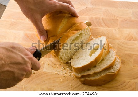 slicing bread on wood cutting board with a bread knife
