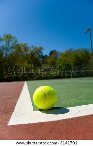 Bright greenish, yellow tennis ball on freshly painted cement court