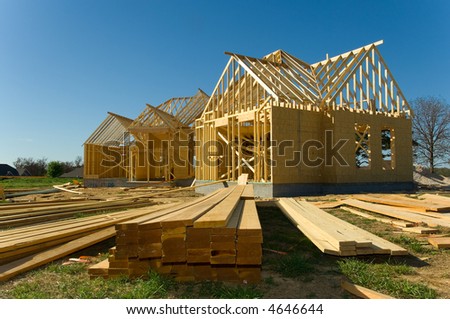 New home under construction with wood, trusses and supplies against blue sky