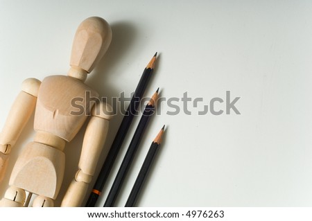 Drawing supplies including drawing pencils a wooden poser on a white sketch pad, the texture of the sketch pad is evident, great space for copy to the right