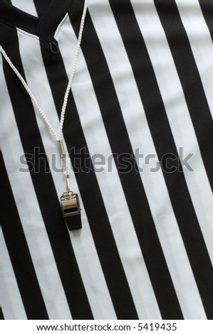 black and white striped referee jersee with a whistle to the left, copy space on the right hand side of image