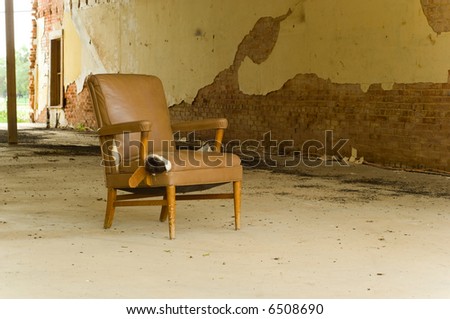 An old abandoned chair left in an abandoned delapidated building.  Interesting how the colors of the building and the chair match- space for copy